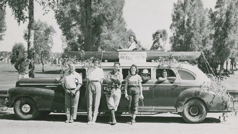 Four people leaning on a car