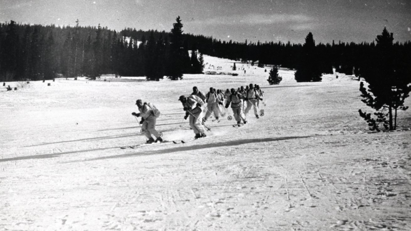 group of men in white uniforms skiing